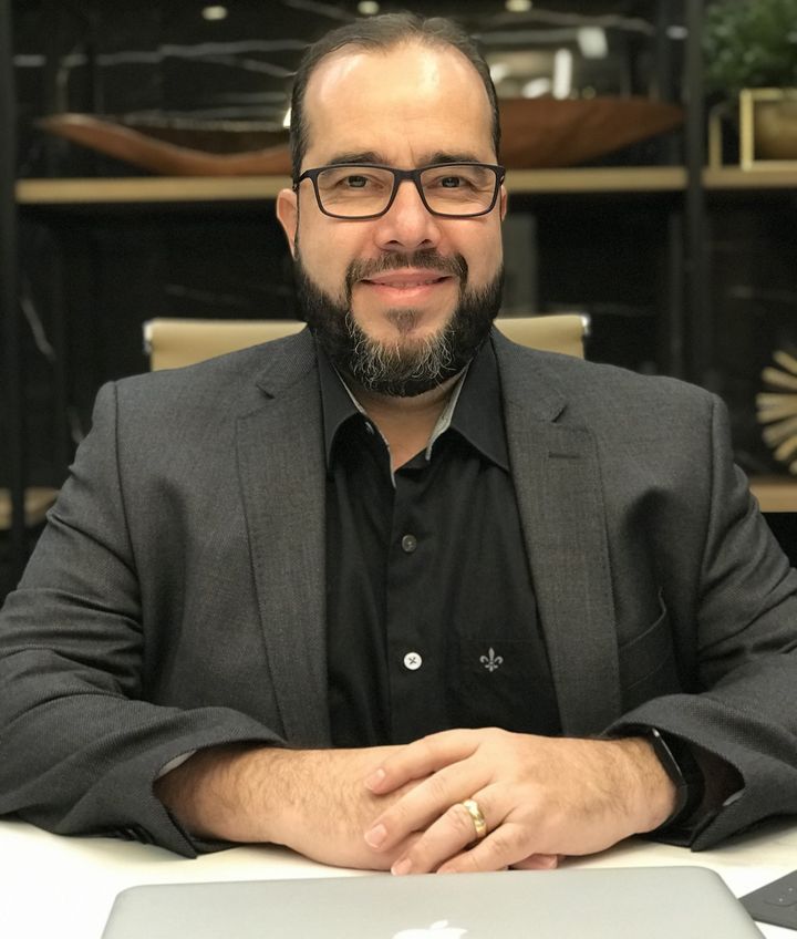 Marco, corretor de imóveis da MGS, sentado à mesa do escritório